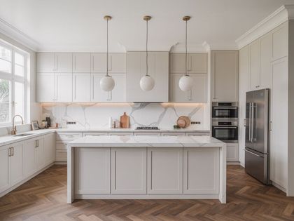 Modern white kitchen with marble countertops, wood floors, and globe pendant lights.