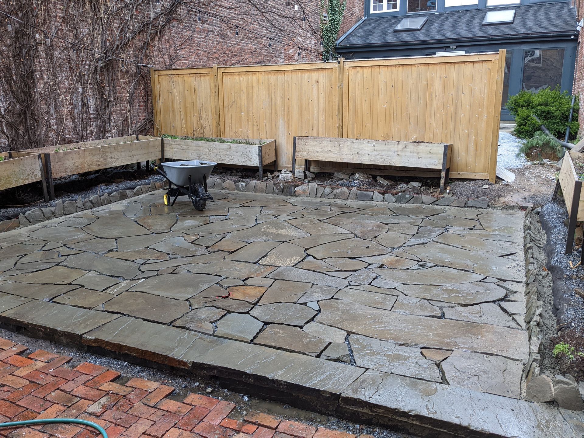 Patio with gray pergola, hot tub, seating area, and potted plants.
