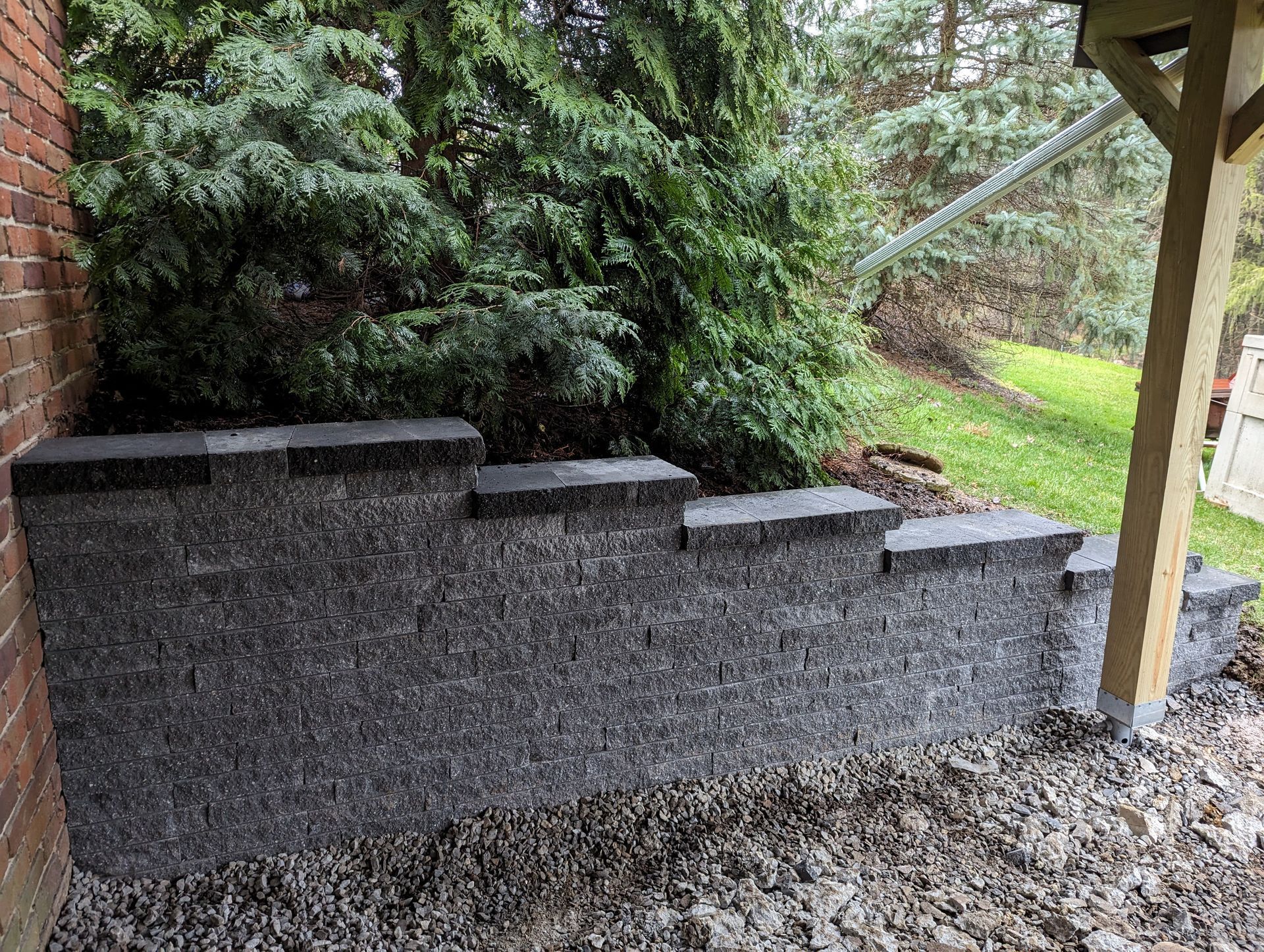 Brick pathway winds through a lush, landscaped garden with trees, shrubs, and grass.