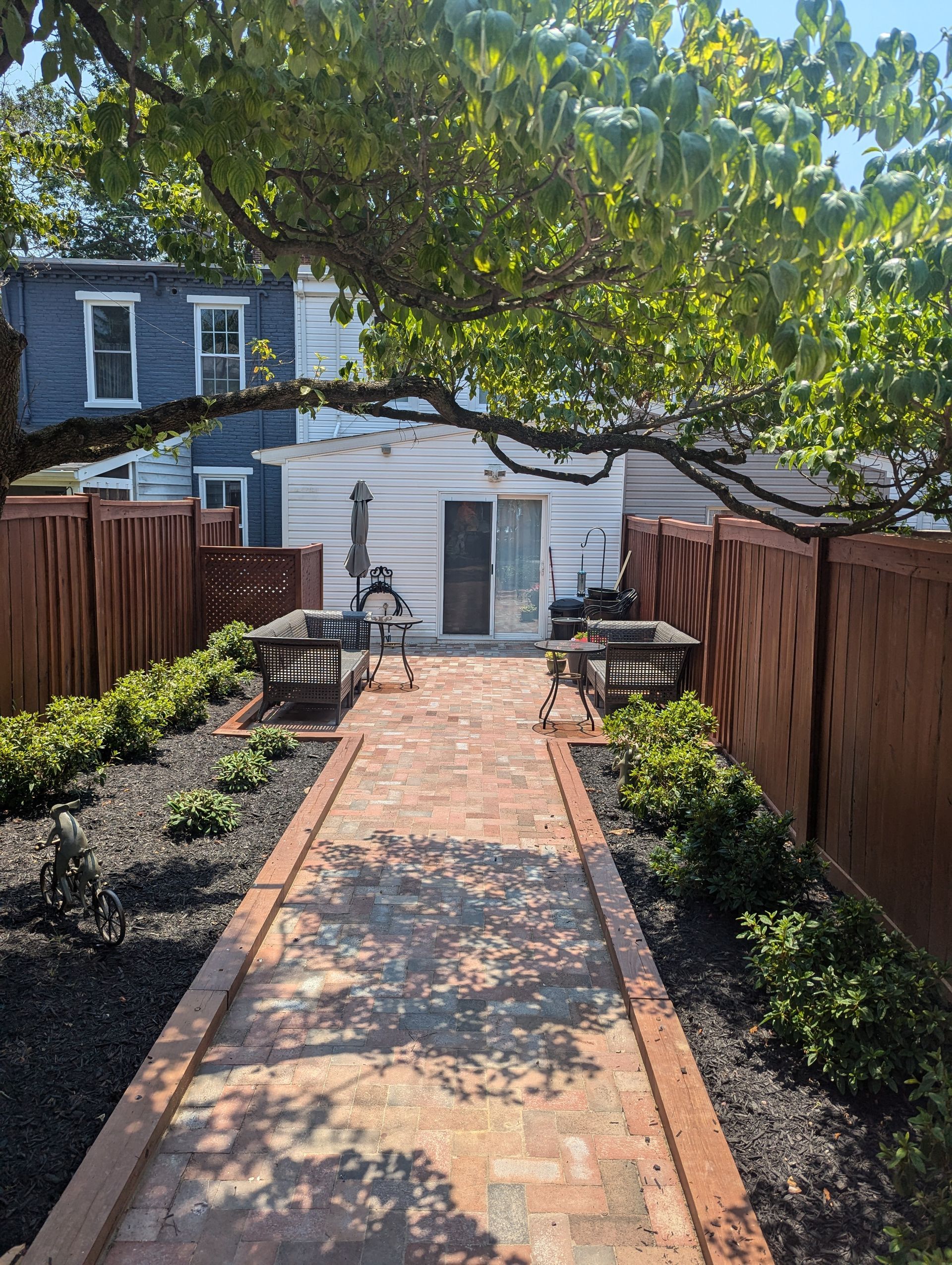 Brick patio with wooden fence, two benches, and a sliding glass door.