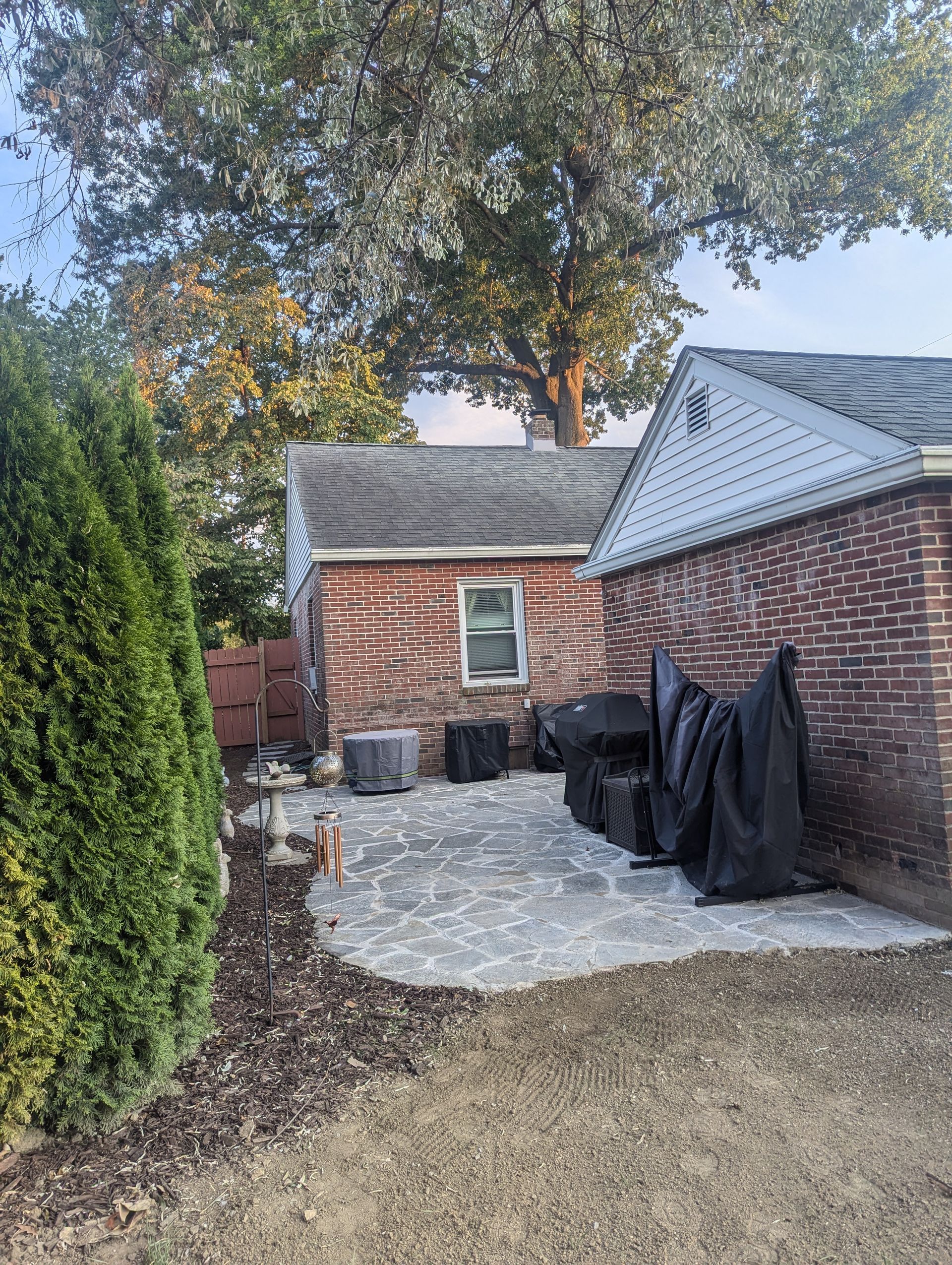 Backyard patio with brick buildings, trees, and landscaping.