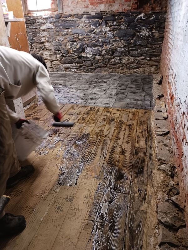 Person applying a sealant to a wooden floor with a roller.