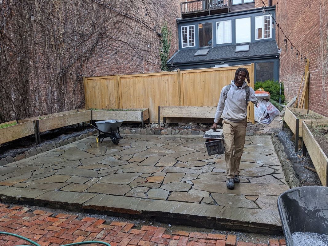 Man walking on new stone patio in a backyard.