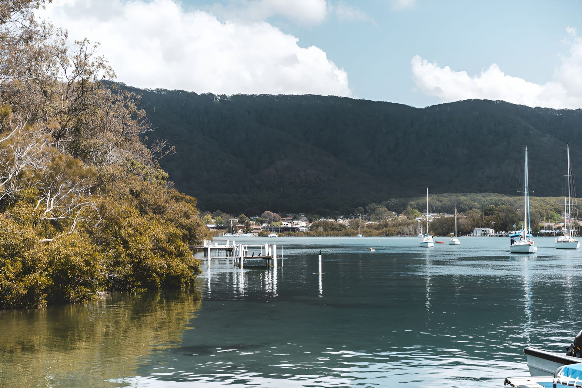 A Body of Water With Boats in It and Mountains in the Background — Town & Country Removals In Laurieton, NSW