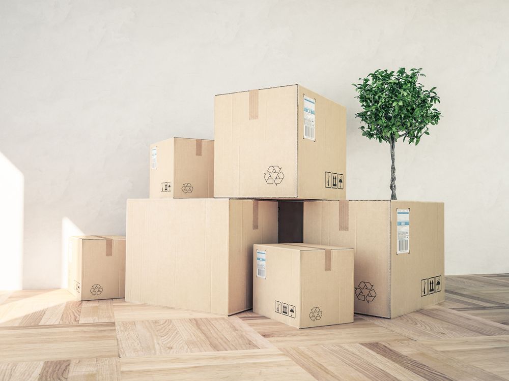 A Bunch of Cardboard Boxes Are Stacked on Top of Each Other on a Wooden Floor — Town & Country Removals In Thrumster, NSW