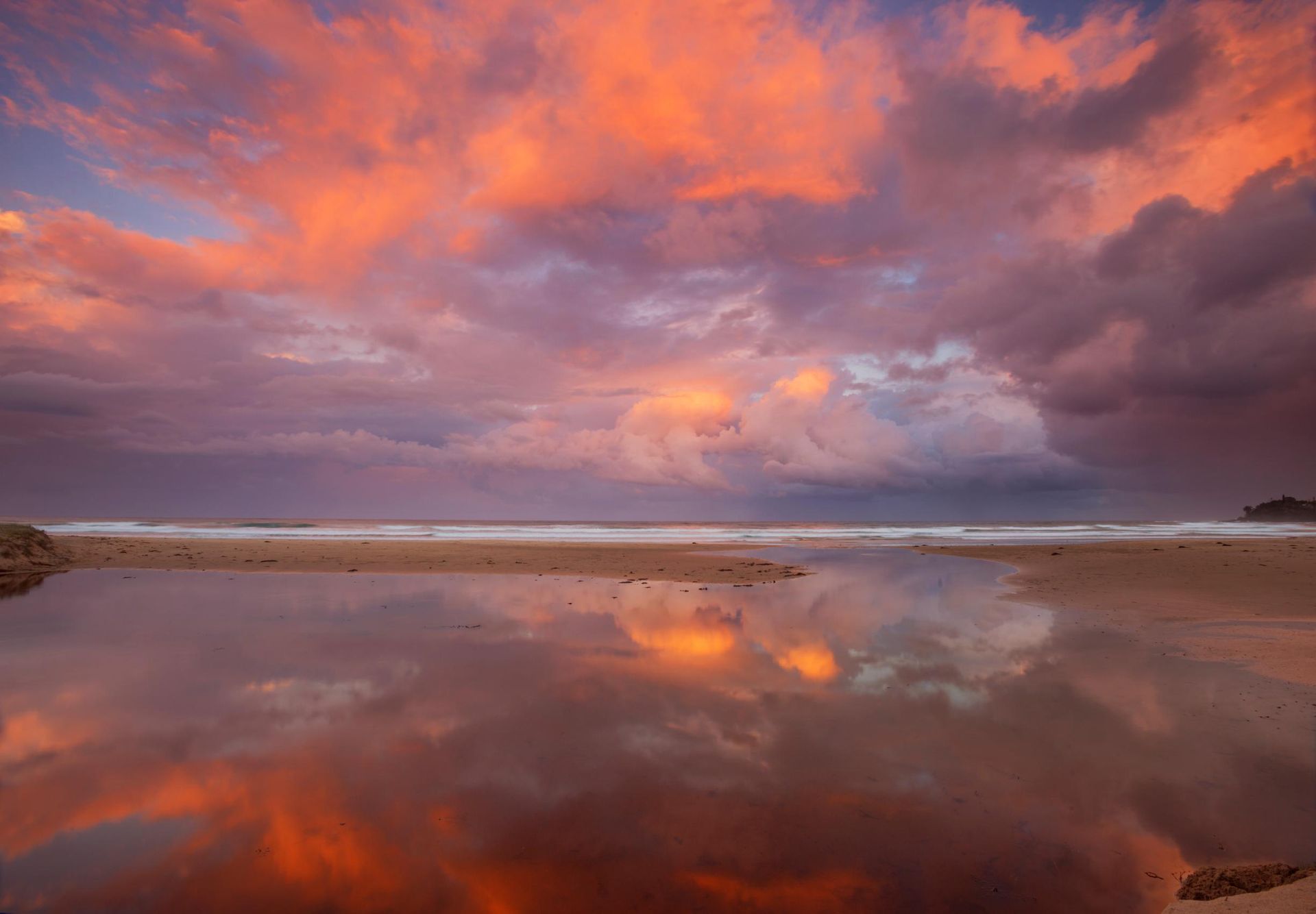 A sunset over a beach with clouds reflected in the water. — Town & Country Removals In Bonny Hills, NSW