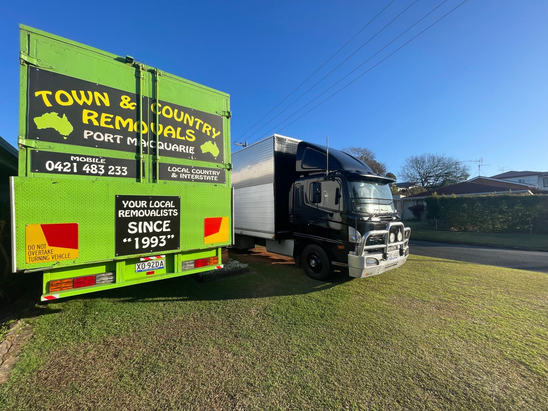 A Green Moving Truck Parked on Grass — Town & Country Removals In Port Macquarie, NSW