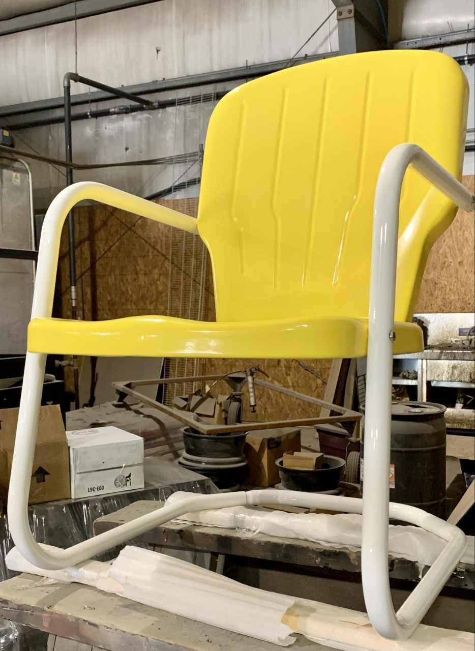 Yellow and white vintage metal lawn chair in an industrial setting.