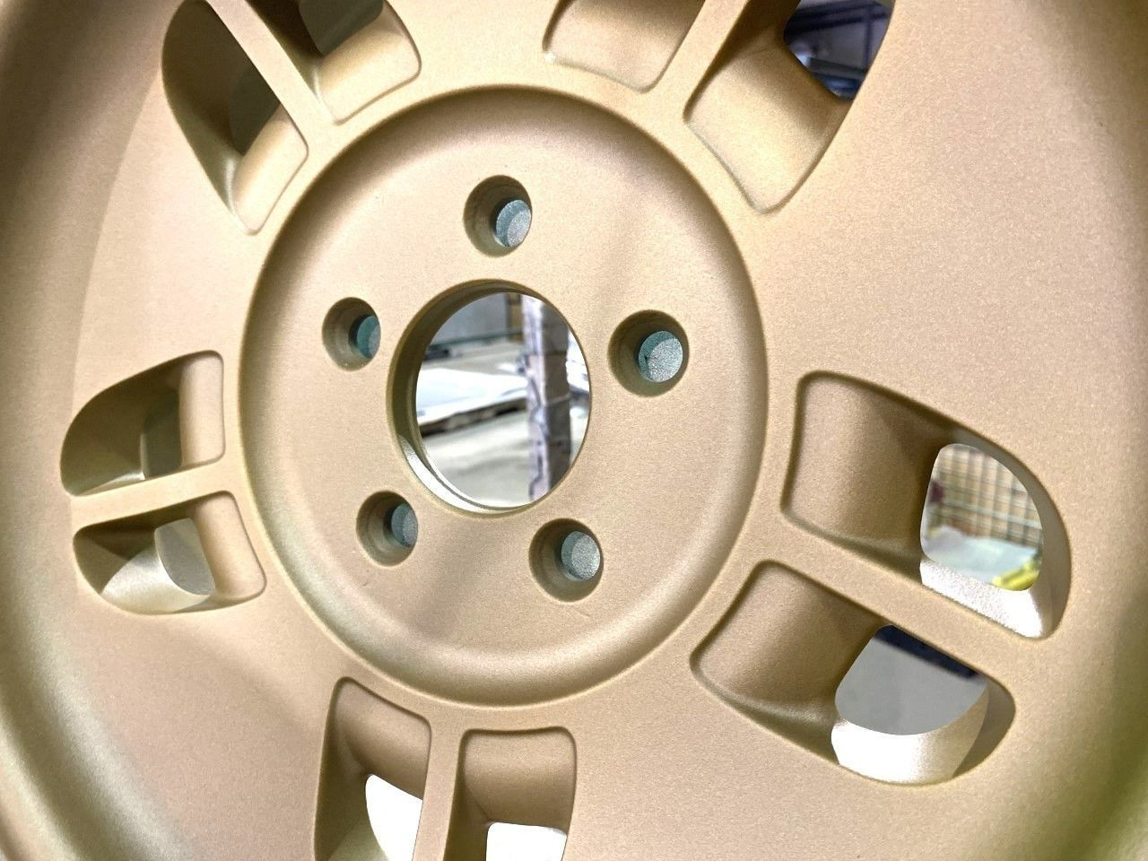 Gold-colored car wheel with five lug nut holes and five open sections.