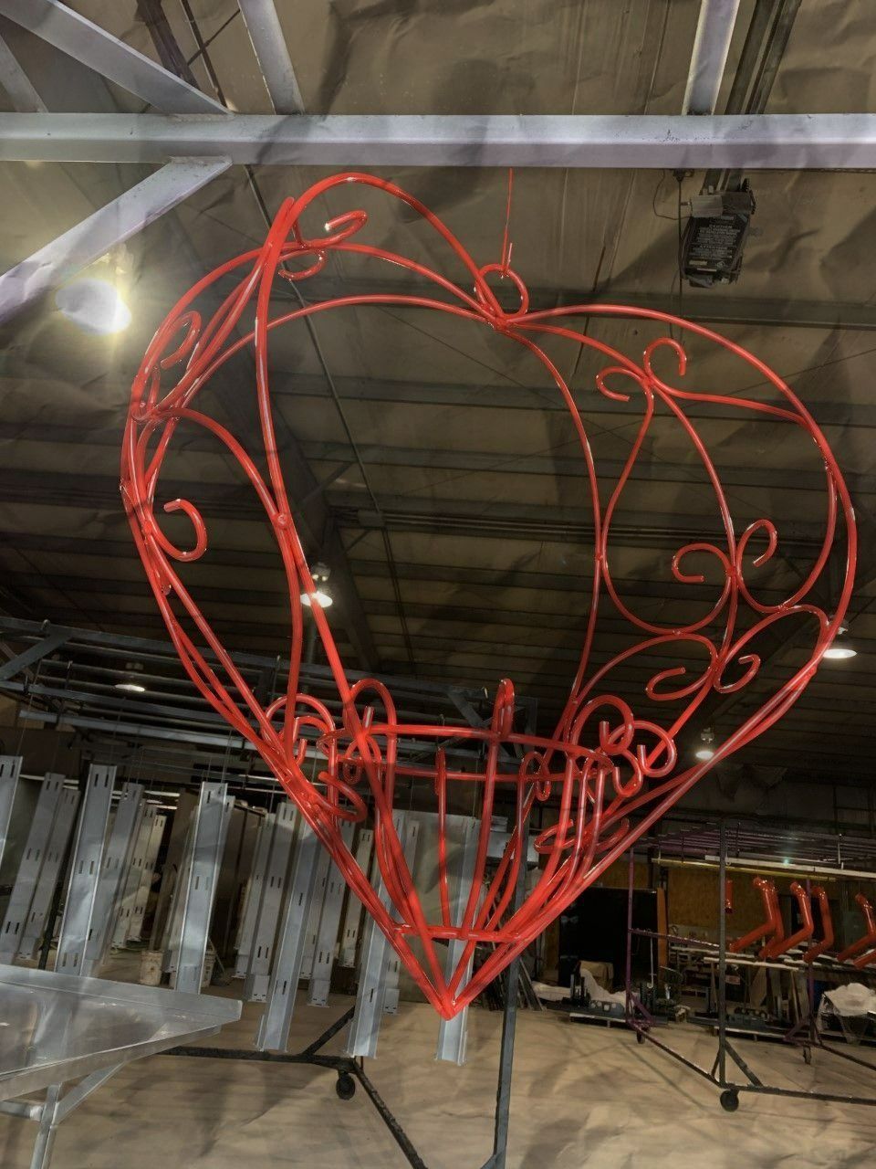 Red heart-shaped decorative structure hanging from ceiling, ornate metalwork design.