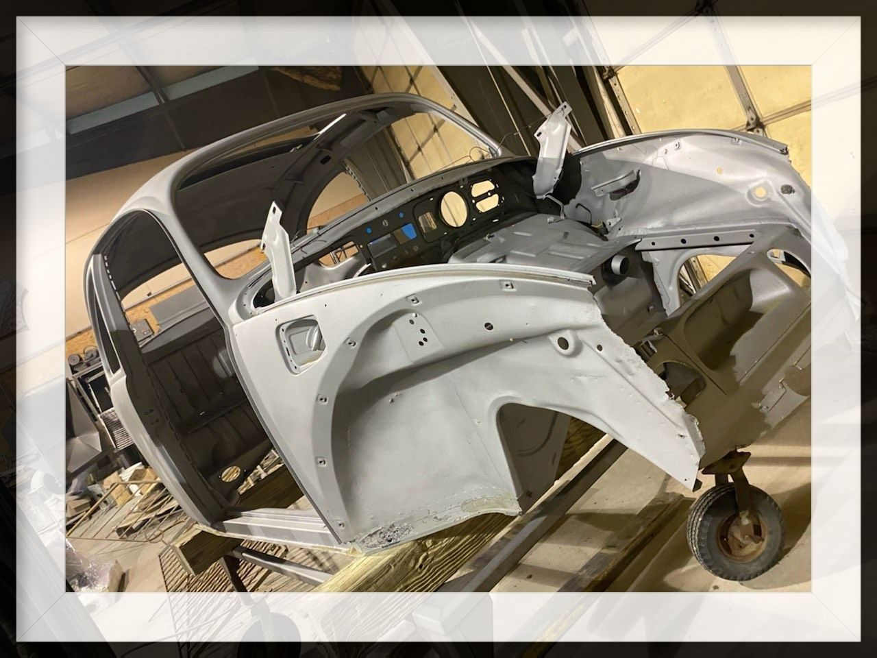 Gray car body shell in a workshop, undergoing restoration.