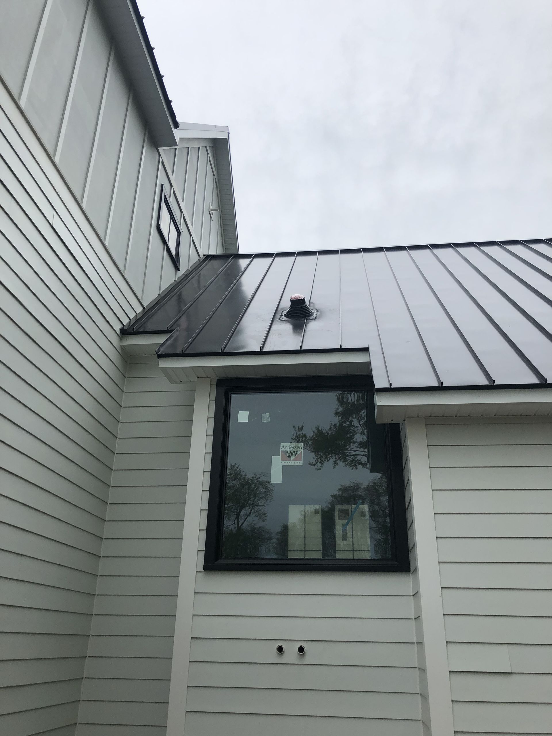 A white house with a black metal 
roof and a window