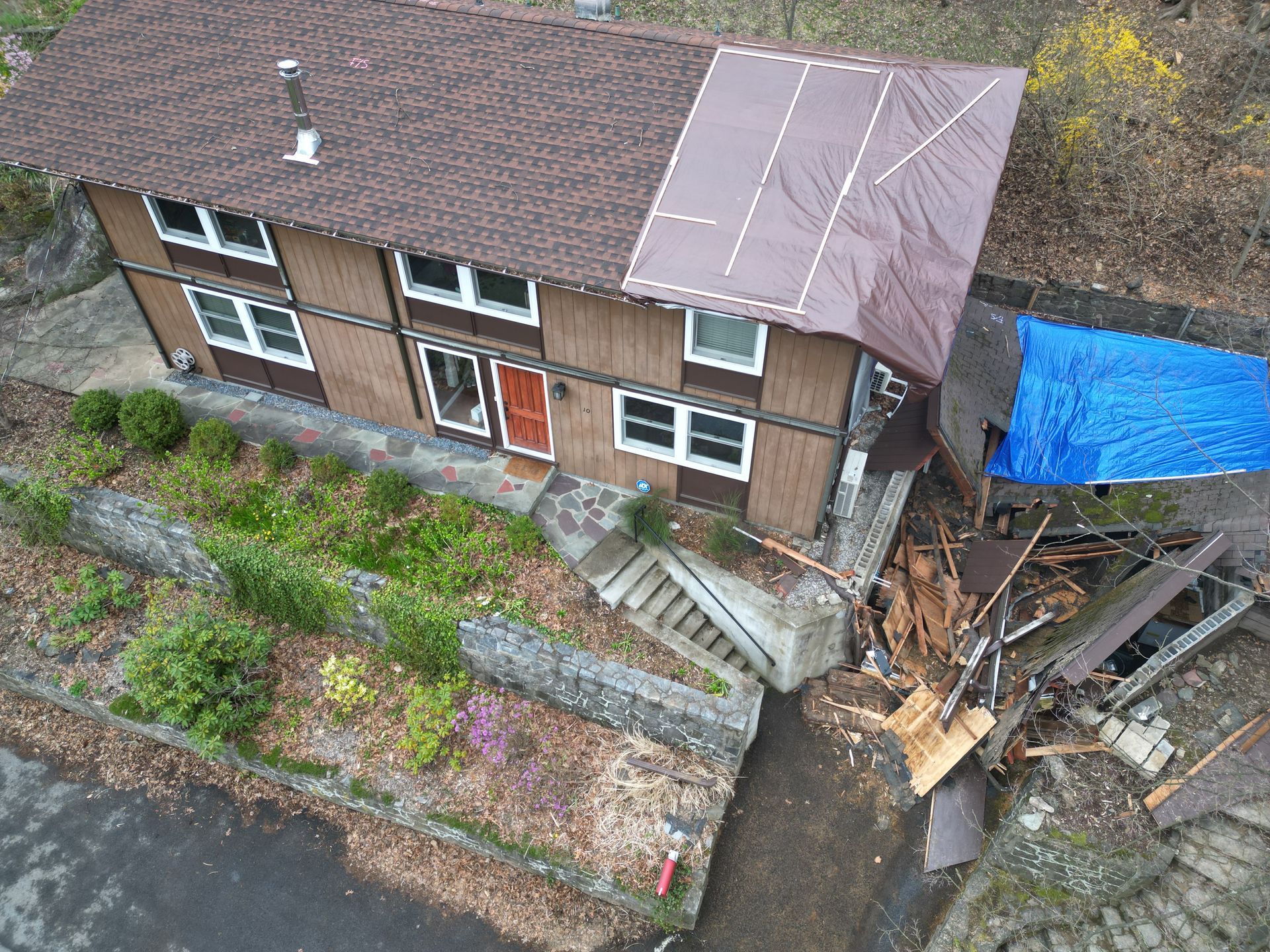 An aerial view of a house with a blue tarp on the ground-storm damage roof repair