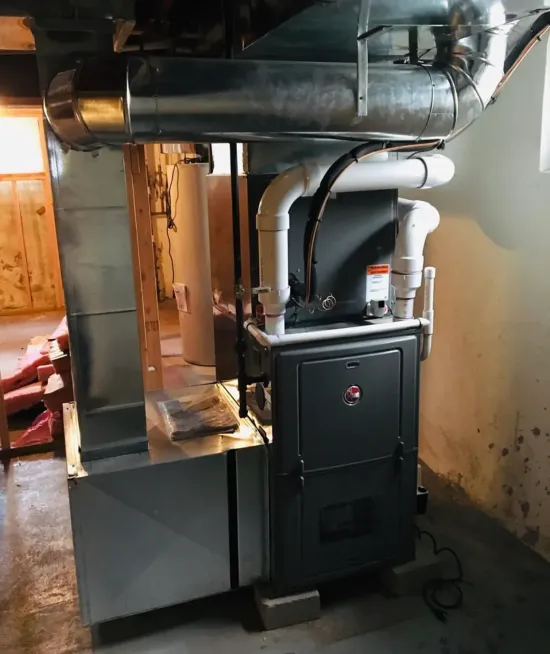Basement furnace and water heater with metal ductwork and white pipes along a wall