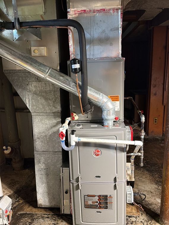 Boiler room with gray HVAC units, exposed pipes, and a water heater on a concrete floor