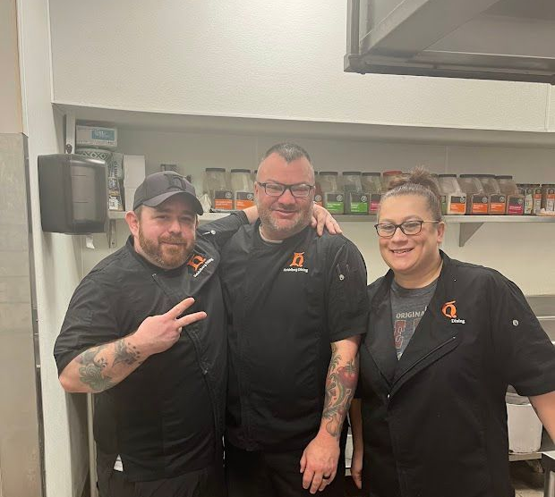 A man in a chef 's hat is posing for a picture with two other chefs