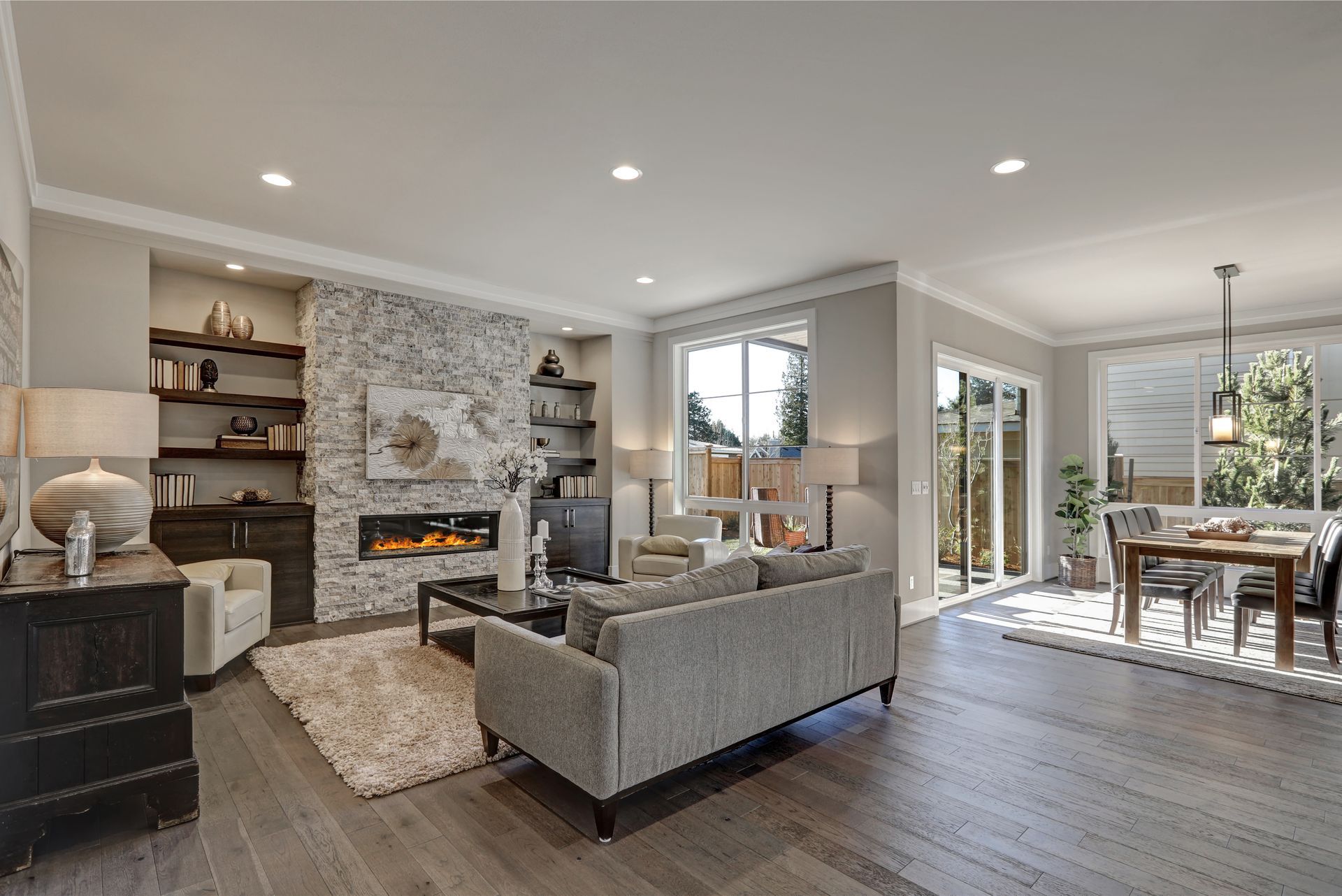 Living room with gray sofa, fireplace, and dining area with access to outdoors.