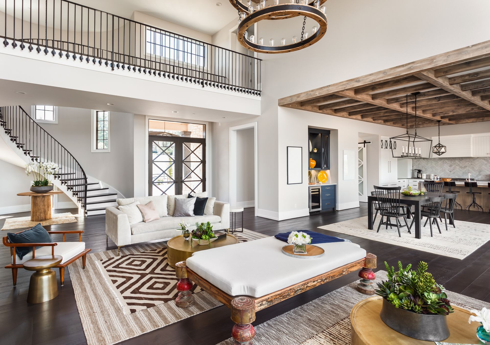 Spacious living room with high ceilings, featuring a sofa, dining table, and staircase leading to a balcony.