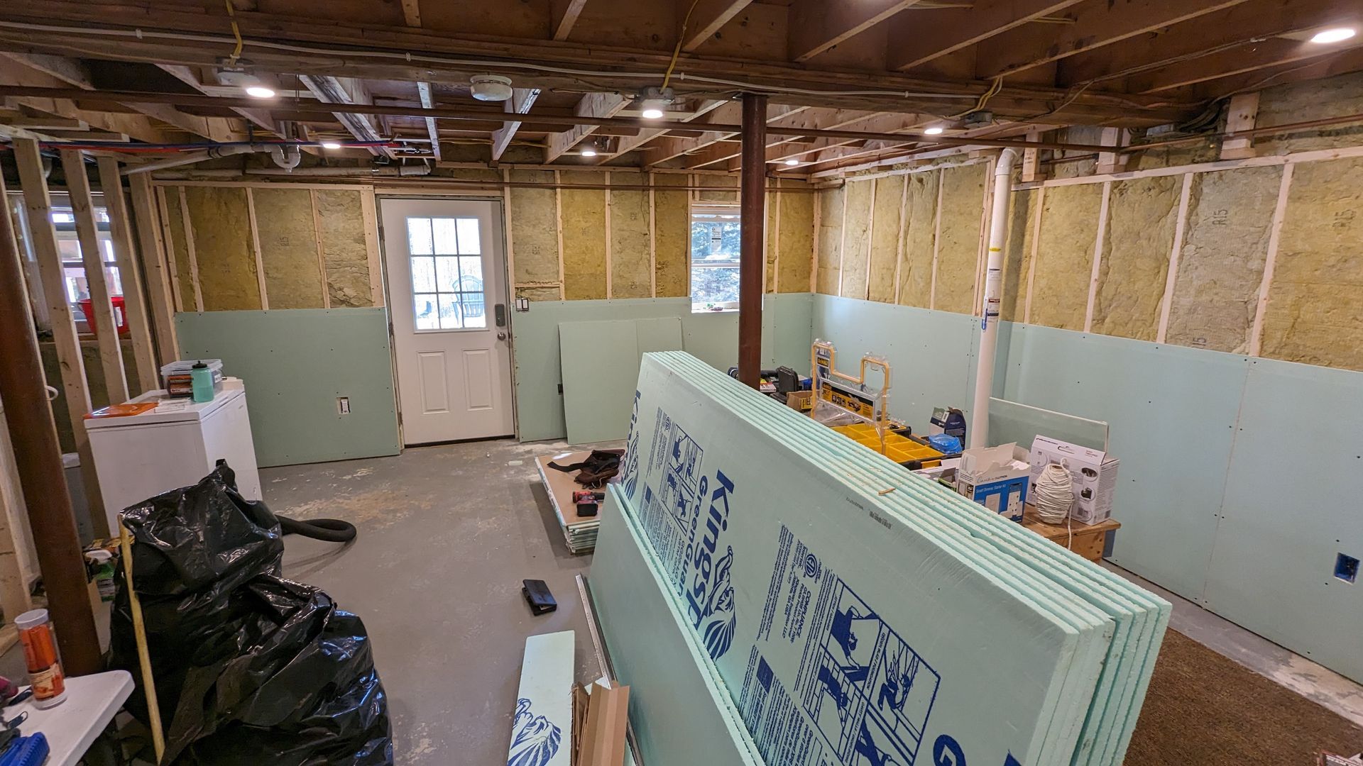 A basement is being remodeled and there is a stack of styrofoam in the middle of the room.
