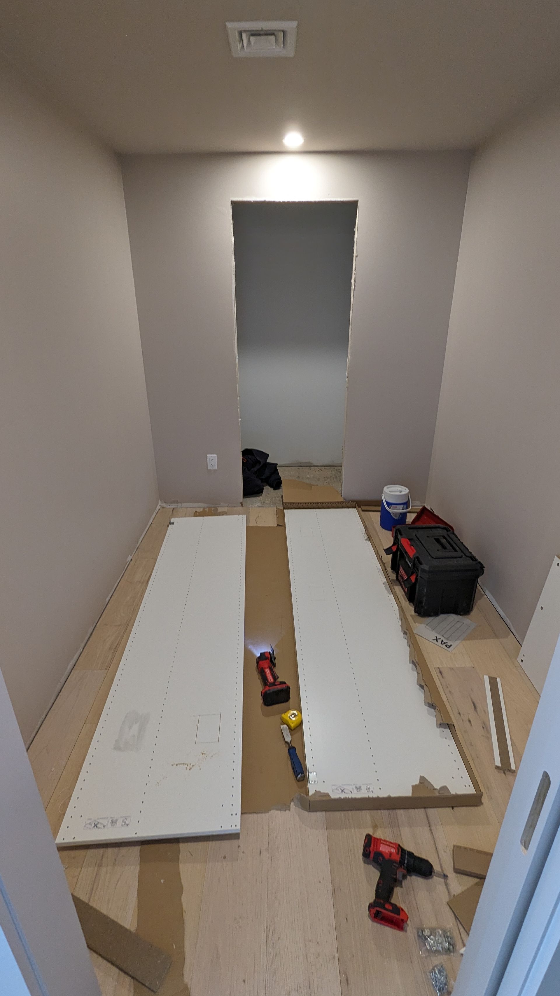 A room with a drill and a few pieces of wood on the floor.