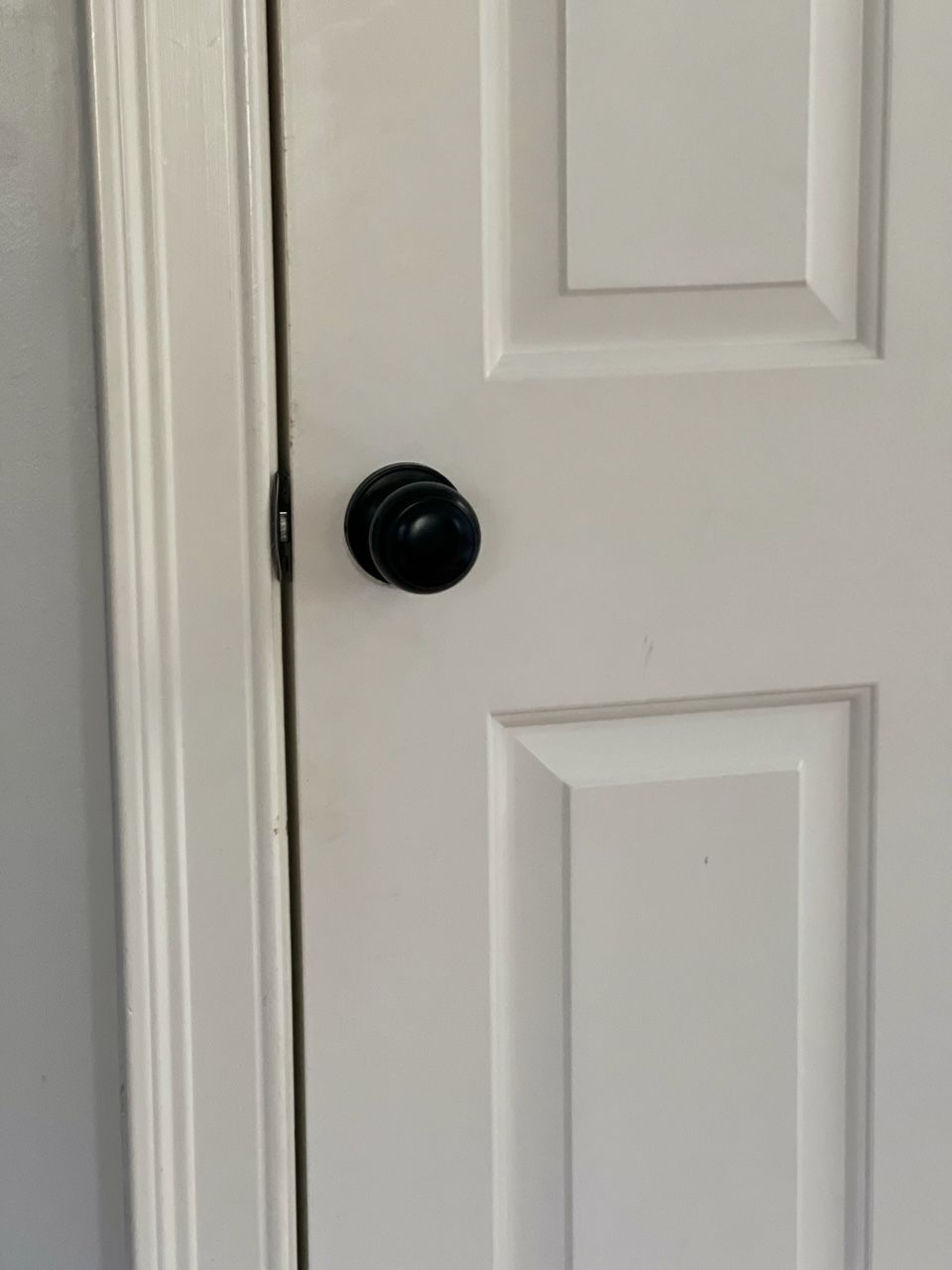 A close up of a white door with a black door knob.