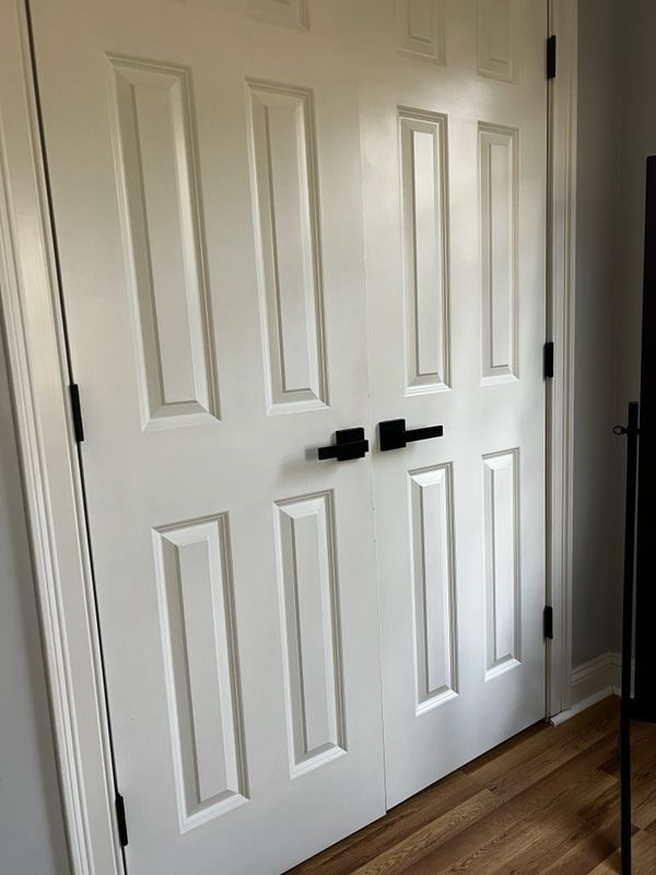 A pair of white doors with black handles in a room.