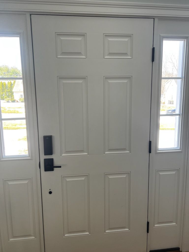A white door with a black handle and two windows in a room.