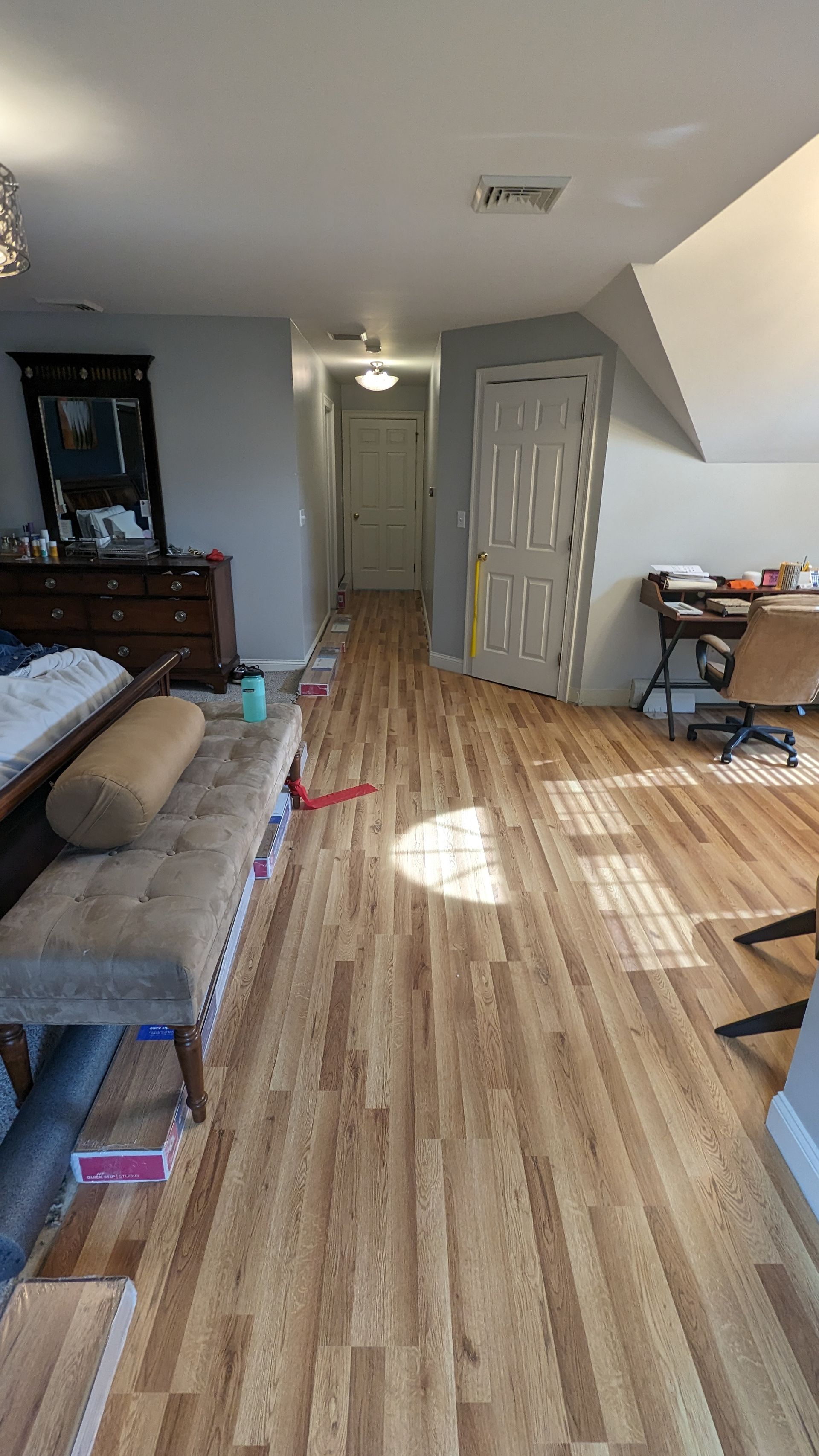 A bedroom with hardwood floors and a desk.