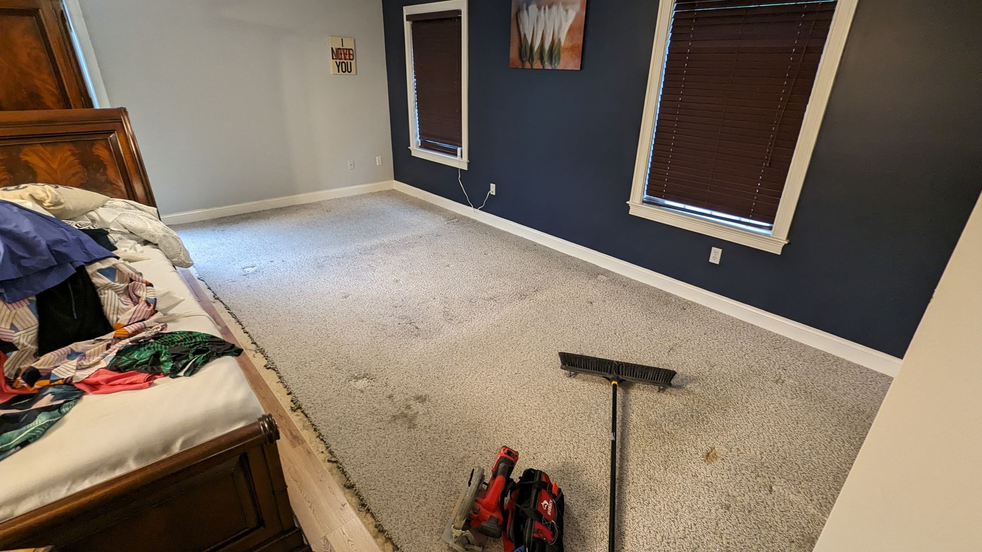 A bedroom with a bed and a broom on the floor.