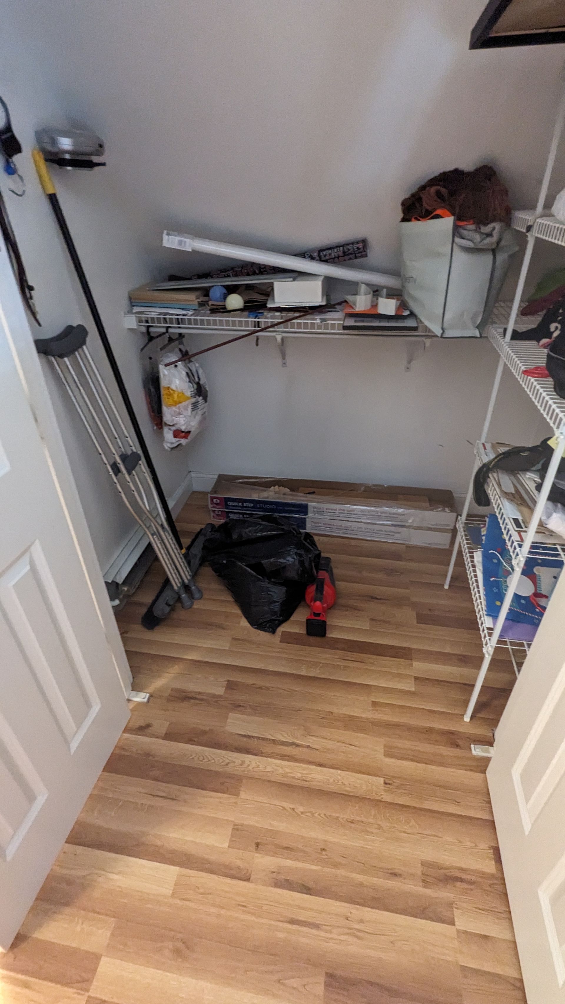 A closet with wooden floors , shelves , and a ladder.