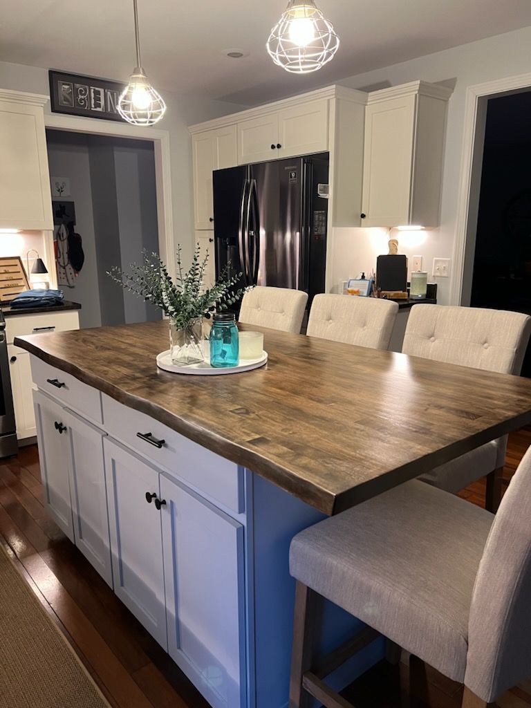 There is a large island in the middle of the kitchen with a wooden counter top.