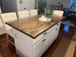 A kitchen island with a wooden top and white cabinets.