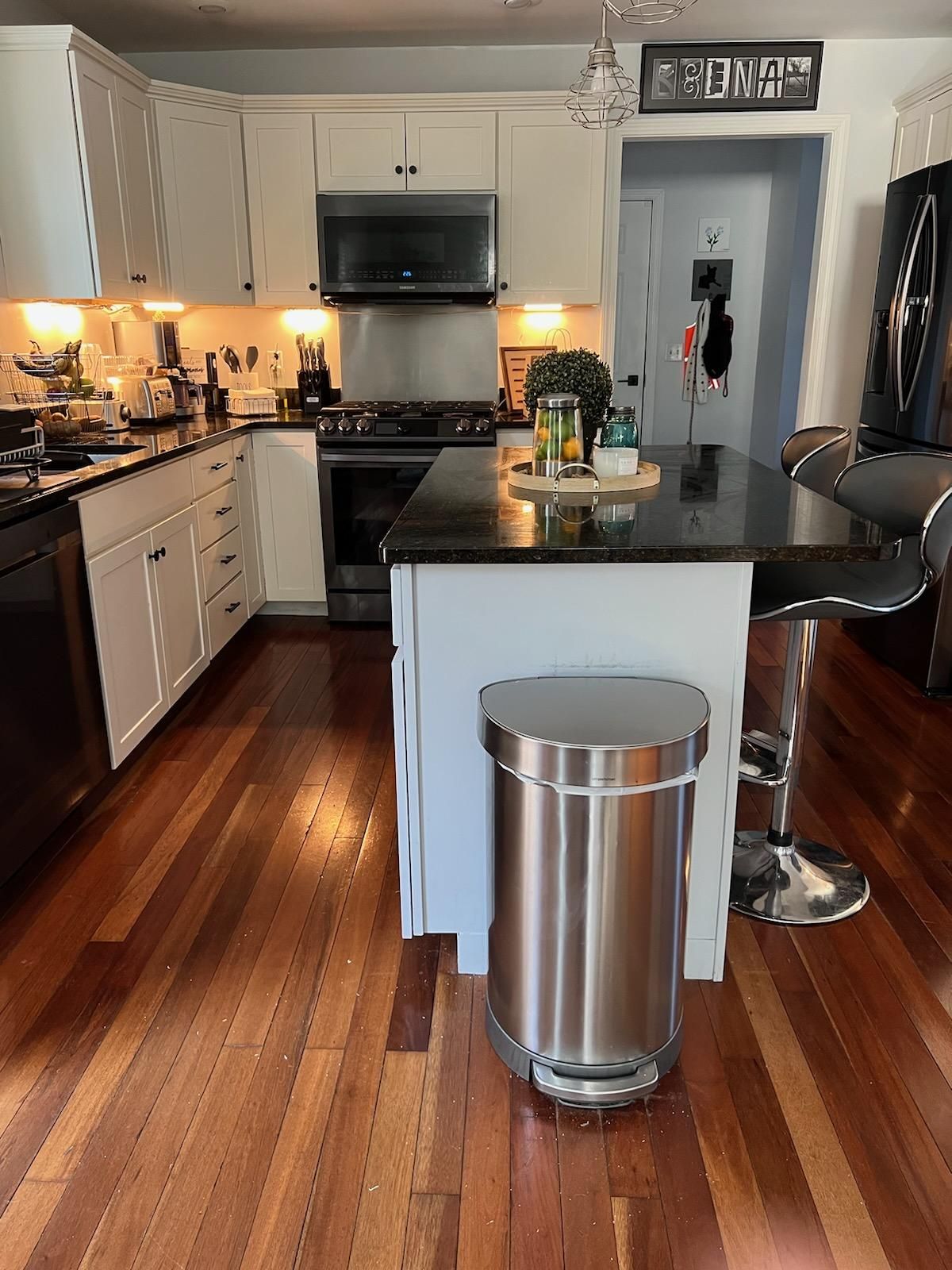 A kitchen with a stainless steel trash can on the floor