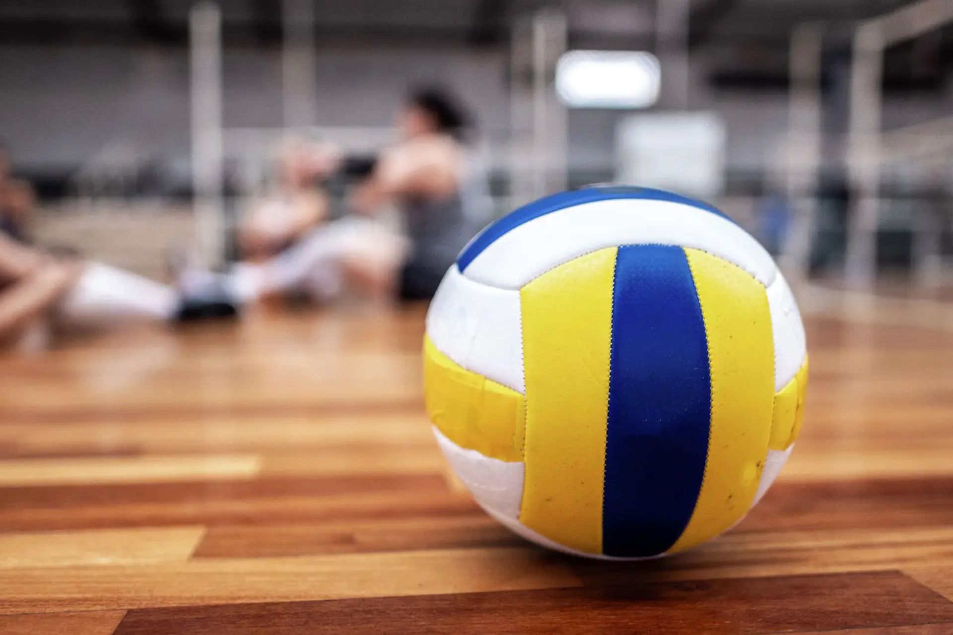 Palla da pallavolo bianca, gialla e blu su un campo di legno