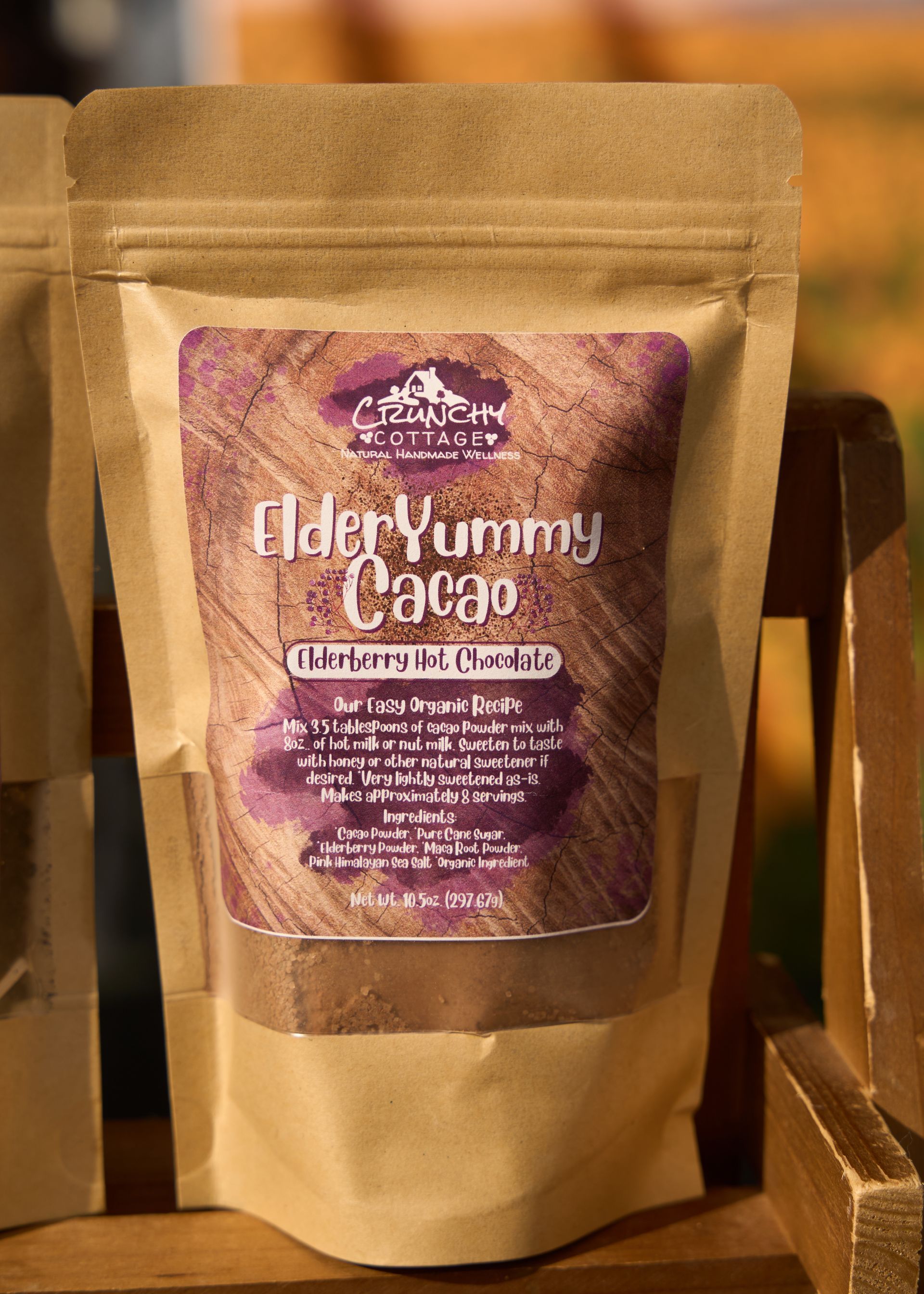 Brown pouch of Elder Yummy Cacao featuring a purple label displayed on a wooden shelf at the Loomis Community Farmers Market