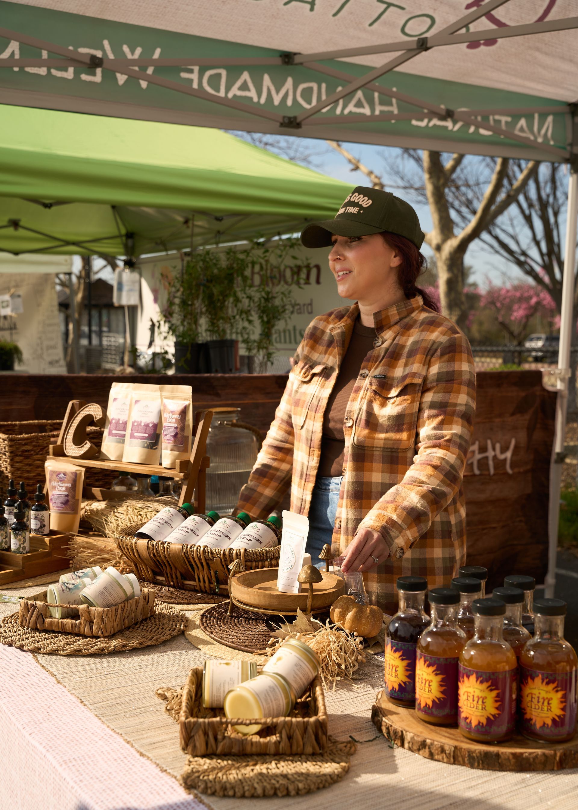 Vendor selling jars of raw local honey and fresh baked goods at an outdoor stall under a green canopy at the Loomis Community Farmers Market
