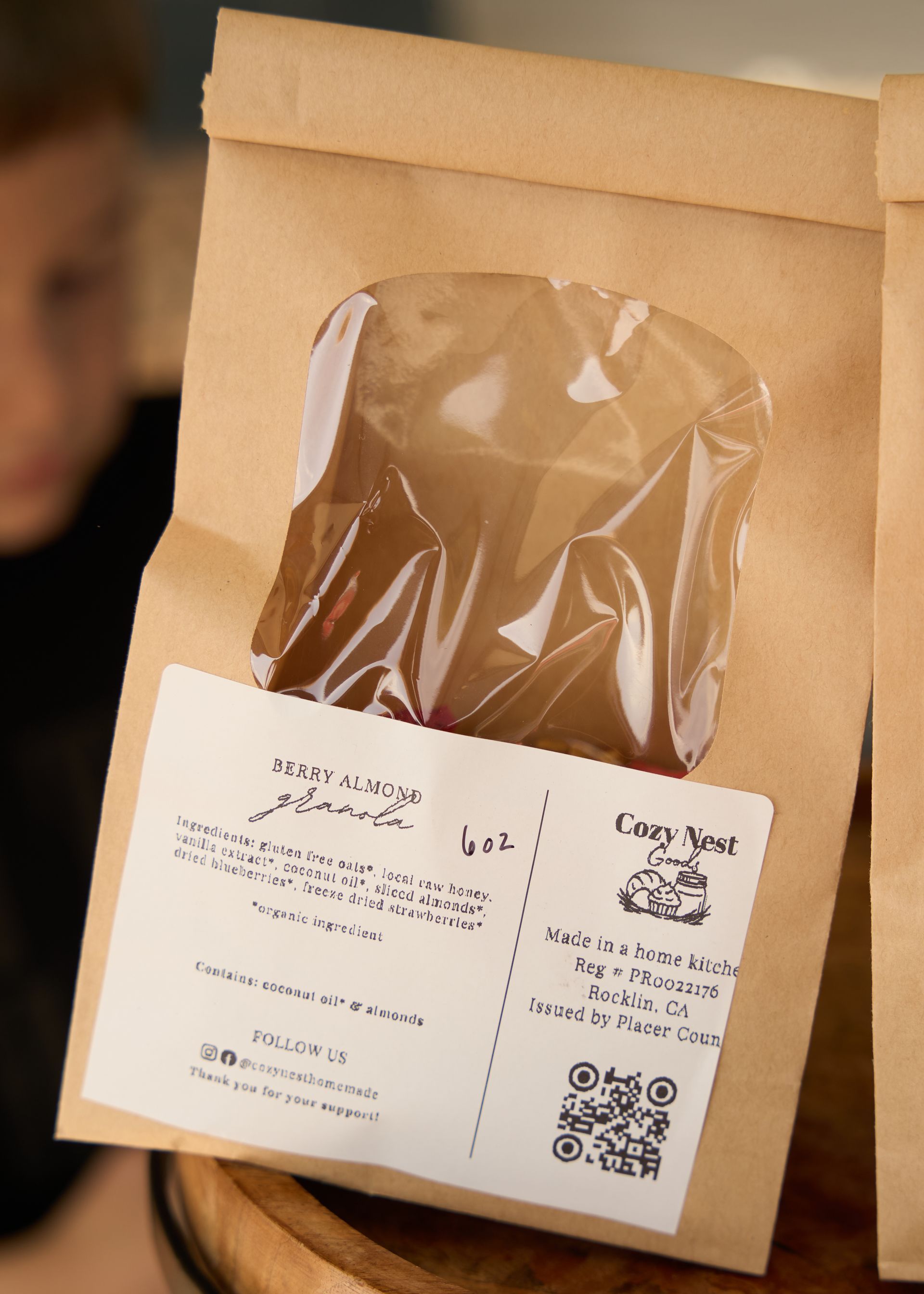 Clear product pouch on a brown kraft paper bag with a scannable QR code label displayed at the Loomis Community Farmers Market