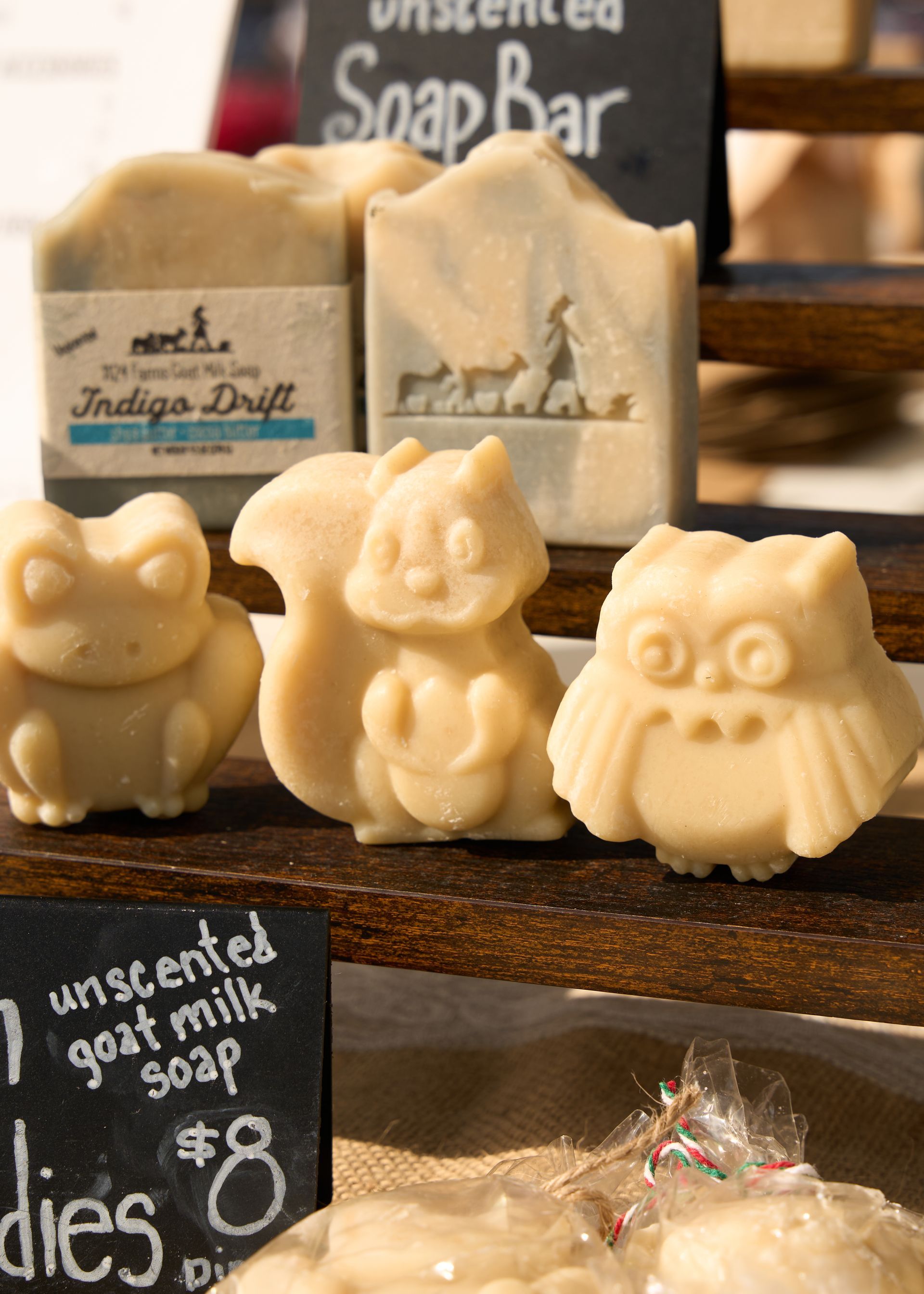 Handmade animal-shaped soap bars displayed on a market stall with chalkboard price signs at the Loomis Community Farmers Market