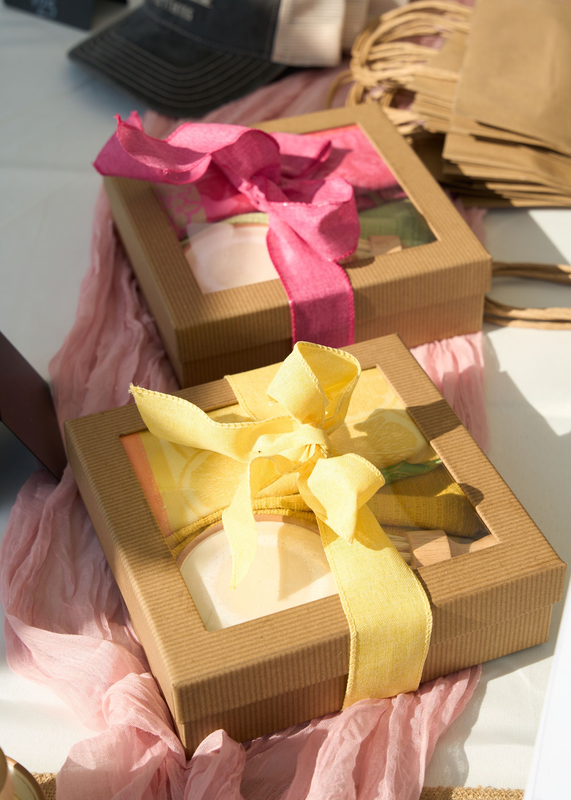 Two gift boxes wrapped with pink and yellow ribbon bows set in tissue paper on a display table at the Loomis Community Farmers Market