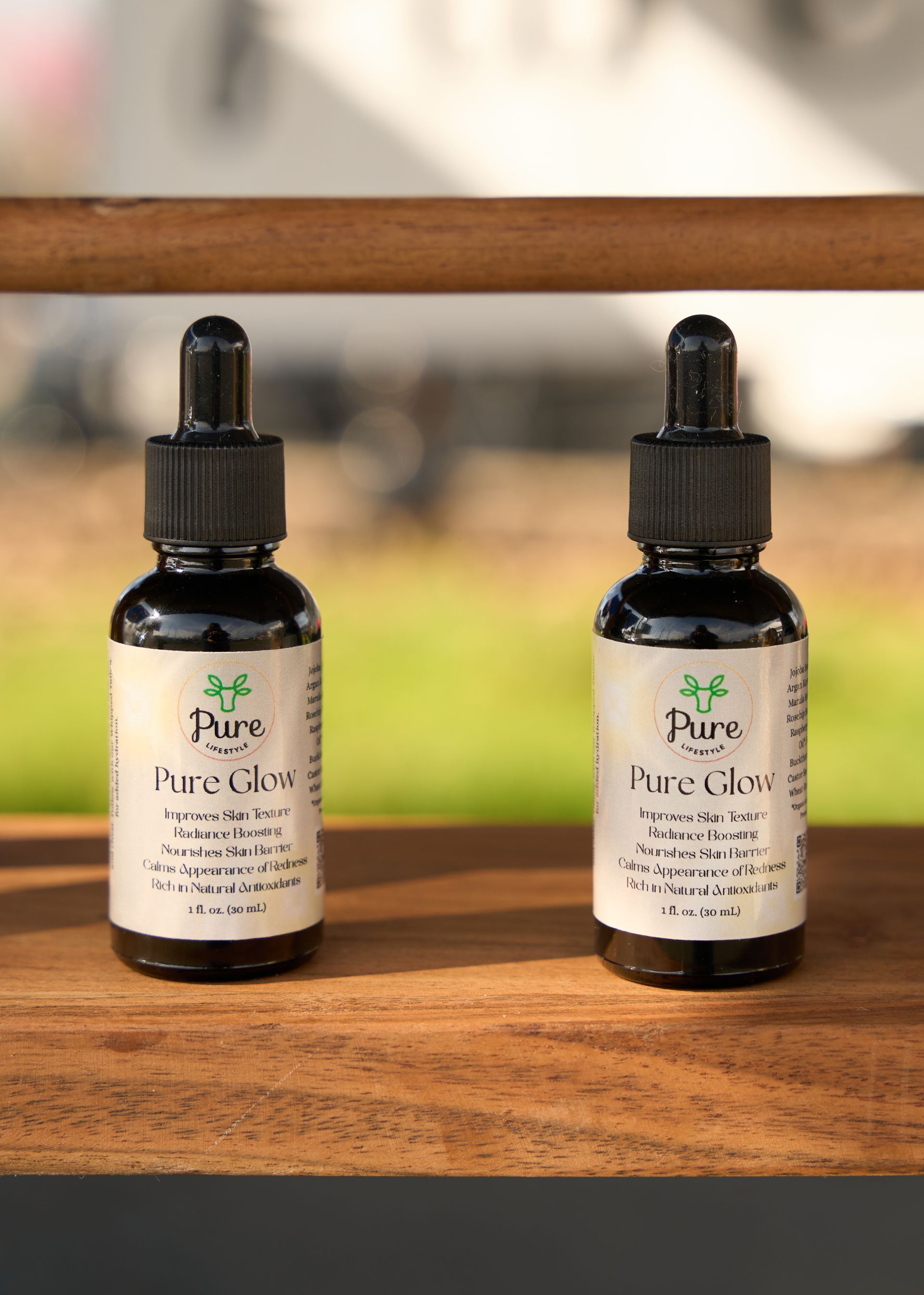 Two black glass tincture dropper bottles labeled Pure+ standing on a rustic wooden surface at the Loomis Community Farmers Market