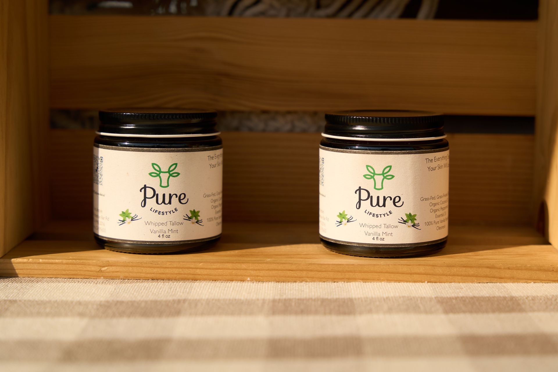 Two jars labeled Pure resting on a striped cloth on a rustic wooden shelf at the Loomis Community Farmers Market