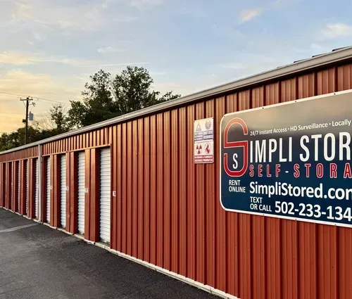 Red storage units with a Simpli Storage sign on a long building at sunset.