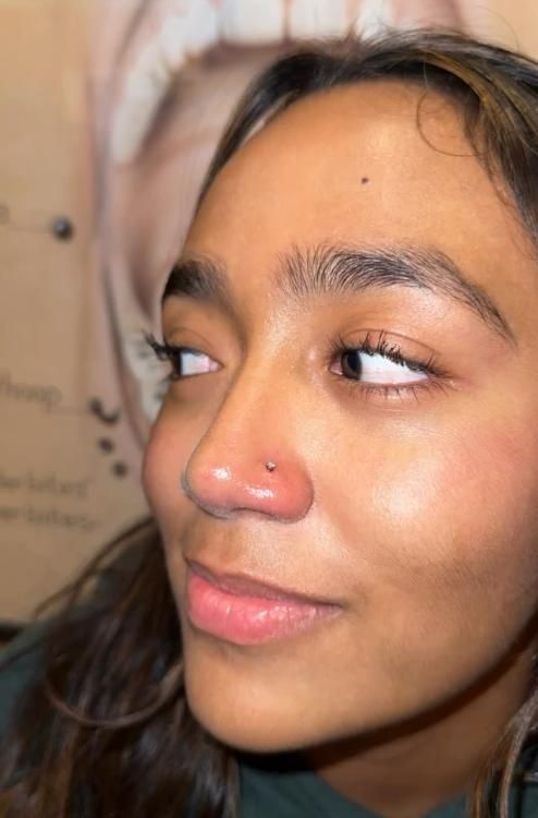 Woman with a nose piercing, looking to the side with a slight smile.