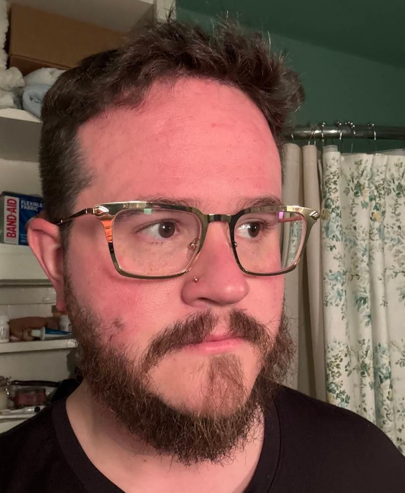 Man wearing glasses with a beard, looking off-camera. 