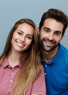 A man and a woman are posing for a picture together and smiling.