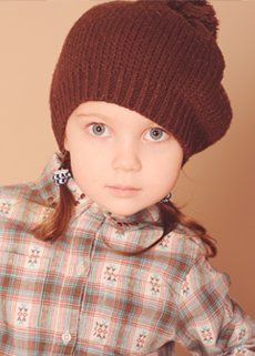A little girl wearing a brown hat and a plaid shirt.