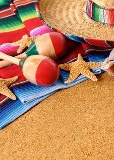 A straw hat , maracas , starfish , and a sombrero are on the sand.