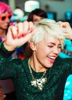 A woman with short blonde hair is dancing at a party.