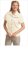 A woman wearing a white shirt and khaki pants is smiling.