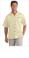 A man wearing a yellow shirt and khaki pants is standing with his hands in his pockets.